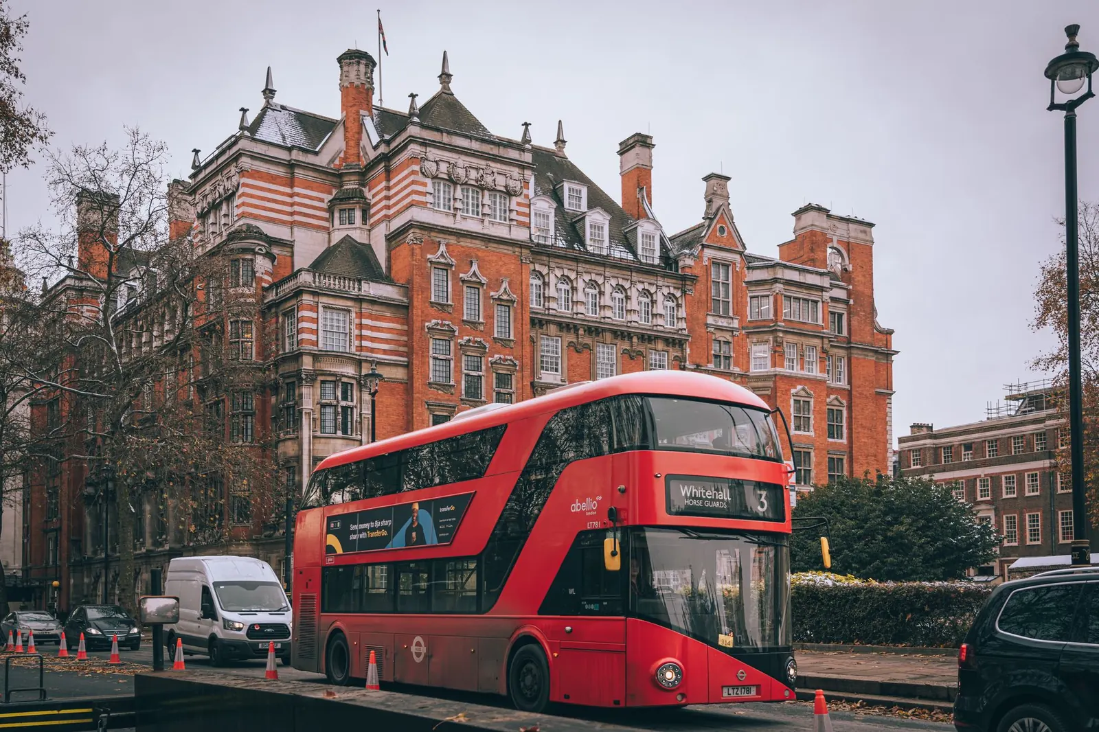 Piros emeletes busz egy londoni utcán turisták előtt napsütésben