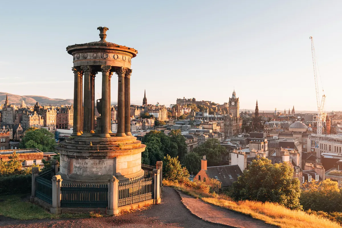 Edinburgh látképe a Calton Hillről naplementében, előtérben a Dugald Stewart-emlékművel