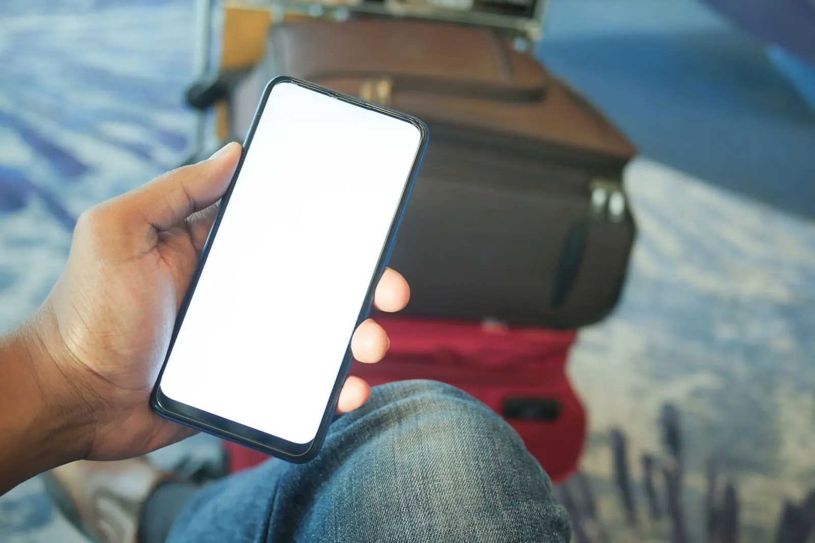Utazó a kezében tartja a telefonját az ETA kérelem kitöltése közben