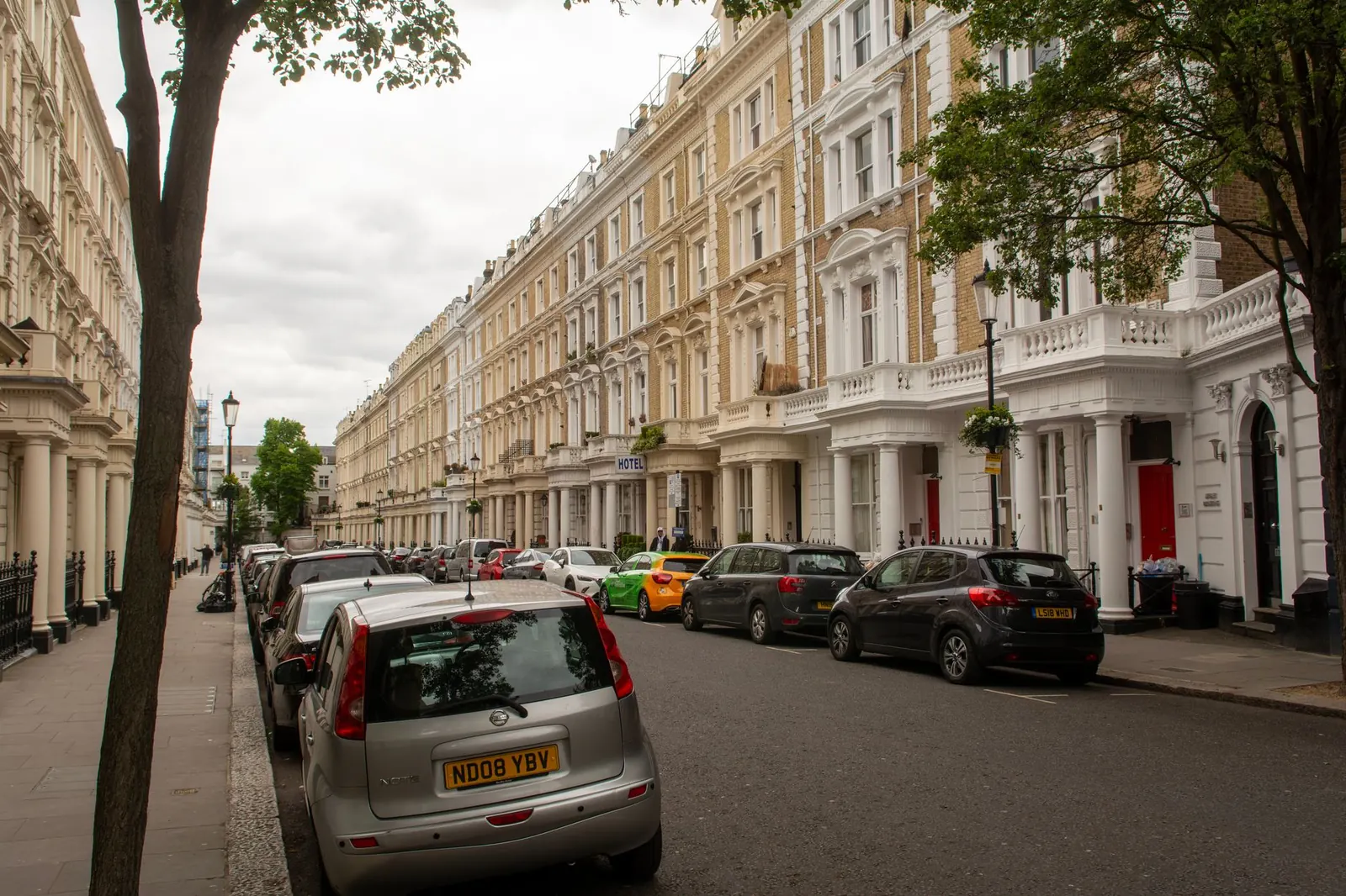 Klasszikus londoni sorházak parkoló autókkal egy csendes utcában