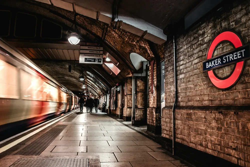 A londoni metró Baker Street állomásának téglafalú peronja egy beérkező szerelvénnyel